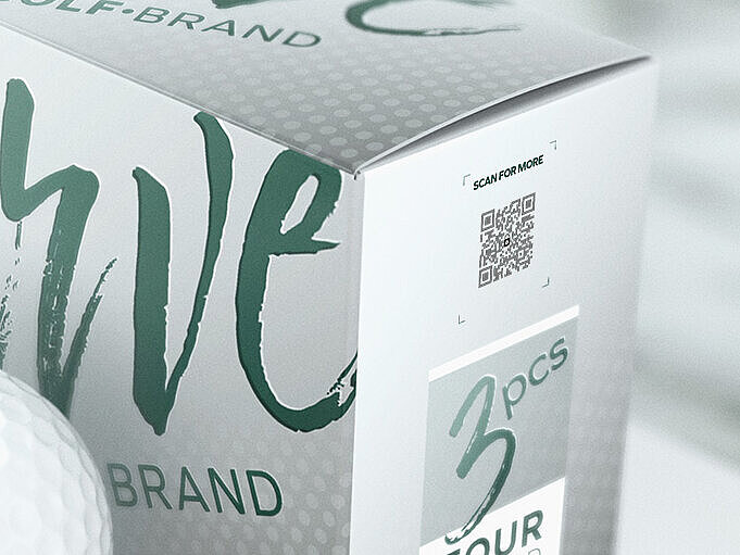 一盒“Verve Golf Brand”Tour Speed高尔夫球，旁边摆放着一颗白色高尔夫球。包装采用防伪码ValiGate®直接打印技术，将防伪功能直接嵌入包装上印制的QR码中。这样，无需额外标签即可实现无缝产品认证和详细产品信息访问，确保解决方案安全环保。